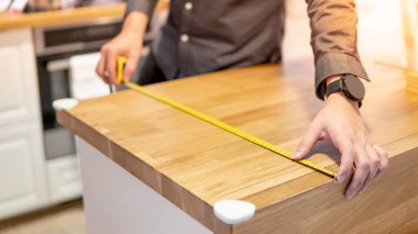 Tezgahüzerinde bant ölçüsü kullanan erkek el