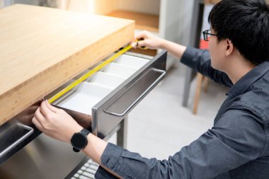 Asyalı adam çekmecede bant ölçüsü kullanarak