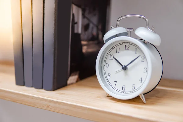 Orologio da tavolo bianco su libreria in legno — Foto Stock