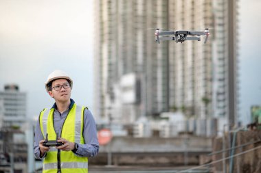 Asyalı mühendis şantiye üzerinde drone uçan