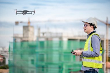 Asyalı mühendis şantiye üzerinde drone uçan