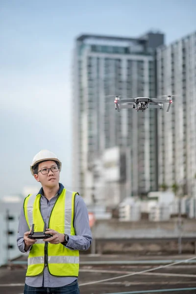 Asian engineer flying drone over construction site