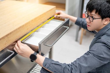 Asyalı adam çekmecede bant ölçüsü kullanarak