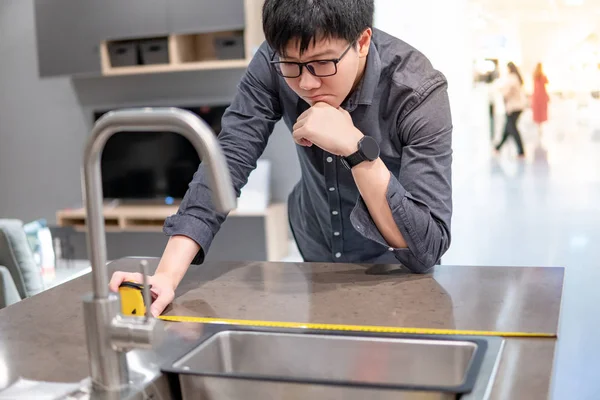 Asian człowiek za pomocą taśmy miara na kuchnia licznik — Zdjęcie stockowe