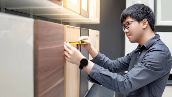 Hombre asiático usando cinta métrica en materiales de gabinete —  Fotos de Stock