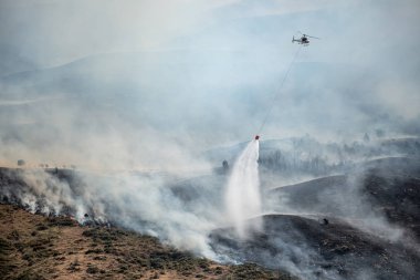 Firefighting helicopter drop water on forest fire clipart