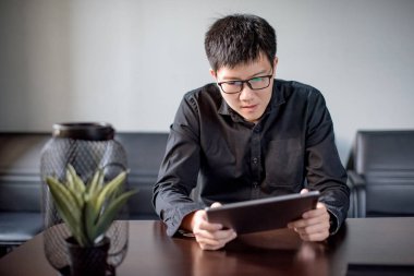 Ofiste dijital tablet kullanan Asyalı işadamı
