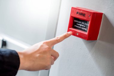 Male hand pointing at red fire alarm switch clipart