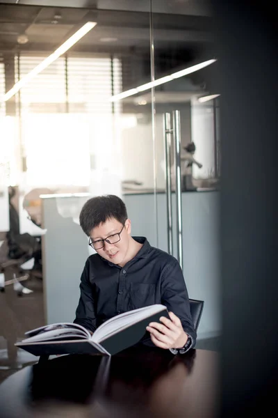 Asiatischer Geschäftsmann liest Buch in Bibliothek — Stockfoto