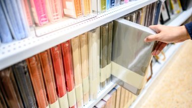 Kırtasiyedeki renkli raf görüntüsünden yeni bir plastik klasör klasörü seçen erkek el. Ofis malzemeleri konsepti satın almak