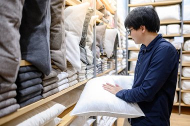 Genç Asyalı müşteri mobilya mağazasında yastık ya da kanepe seçiyor. İç mekan tasarımı için alışveriş evi dekorasyonu. Ev geliştirme kavramı