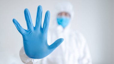 Özel koruyucu ekipman (PPE) giyen doktor veya hekim hastane kliniğinde steril eldiven takıyor. Tıp işçisinin mavi lastik eli. Coronavirus (COVID-19) enfeksiyonunun önlenmesi.