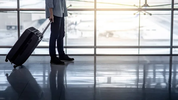 Vacation trip or travel abroad concept. Immigration and baggage claim. Tourist man walking with suitcase luggage waiting for airline flight check-in at international airport terminal.