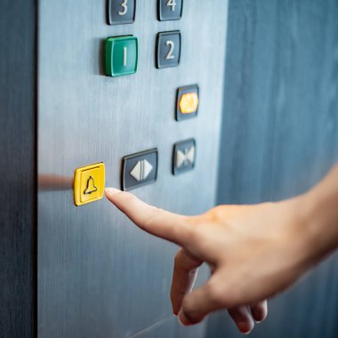 Acil durum durdurma ve Asansör (lift) alarm düğmesine basarak erkek işaret parmağı. Makine Mühendisliği kavramı