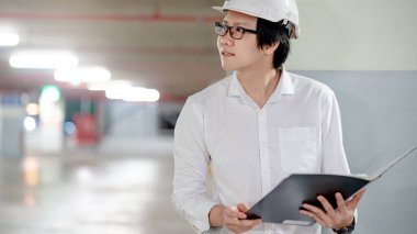 Asyalı inşaat mühendisi ya da koruma kaskı takan inşaat işçisi. İnşaat alanında çalışan erkek mimar. İnşaat ve mimari kavramı