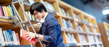 Asyalı bir üniversite öğrencisi, eğitim araştırması için kütüphanede merdivenin başında dururken kitaplıktan kitap seçiyor. Kitapçıda çok satan koleksiyon. Burs ya da eğitim fırsatı