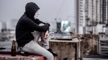 Beyaz maskeli, kapüşonlu, kırık bir alkollü içki şişesiyle terk edilmiş binada oturan gizemli adam kendini yorgun ve stresli hissediyor. Depresyon, akıl sağlığı sorunu veya alkolizm konsepti