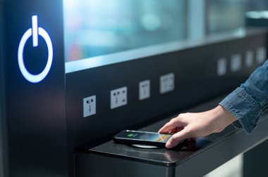 Erkek, akıllı telefonu kablosuz şarj cihazına ya da şarj aletine bağlıyor. Kamu alanındaki cep telefonu elektrik yükleme istasyonu.