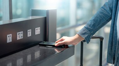 Erkek, akıllı telefonu kablosuz şarj cihazına ya da şarj aletine bağlıyor. Kamu alanındaki cep telefonu elektrik yükleme istasyonu.