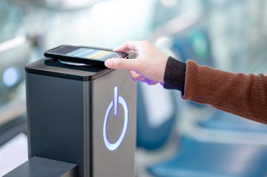 Erkek, akıllı telefonu kablosuz şarj cihazına ya da şarj aletine bağlıyor. Kamu alanındaki cep telefonu elektrik yükleme istasyonu.