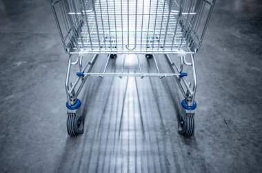 Boş alışveriş arabası ya da market veya marketin beton zemininde alışveriş arabası. Konsept satın alınıyor