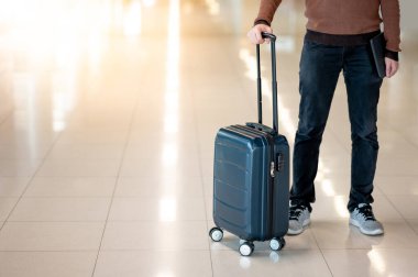Seyahat sigortası konsepti. Bavul ve dijital tablet taşıyan erkek turist havaalanı terminalinde bagaj teslim ve bagaj teslim talebini bekliyor..