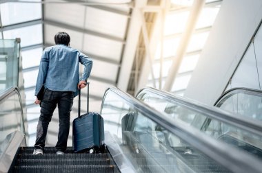 Seyahat sigortası konsepti. Havaalanı terminalinde bavul ve dijital tablet taşıyan Asyalı turist..