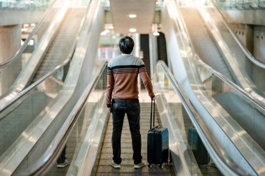 Seyahat sigortası konsepti. Seyahat makinesinde bavul ve dijital tablet taşıyan Asyalı turist ya da havaalanı terminalinde yürüyüş yolu.