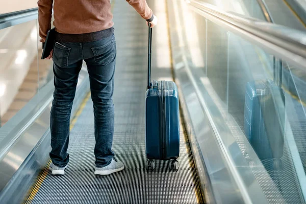 Seyahat sigortası konsepti. Seyahat makinesinde valiz ve dijital tablet taşıyan ya da havaalanı terminalinde yürüyen bir erkek turist.