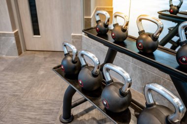 Spor salonunda askıda duran bir grup siyah metal kettlebell. Spor fitness merkezinde ağırlık eğitimi ekipmanları. Kas geliştirme konsepti