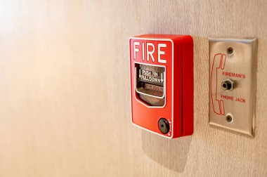 Kırmızı yangın alarmı ve ofis binasındaki ahşap duvardaki itfaiyeci için telefon kablosu. Endüstriyel yangın alarmı sistemi acil durum ekipmanı.