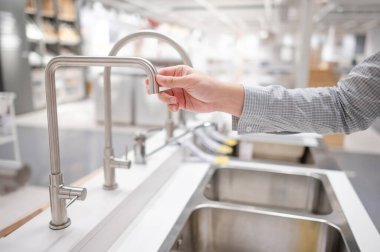 Erkek el mobilya dükkanında paslanmaz çelik musluğu seçiyor. Ev mutfağı için geliştirme.