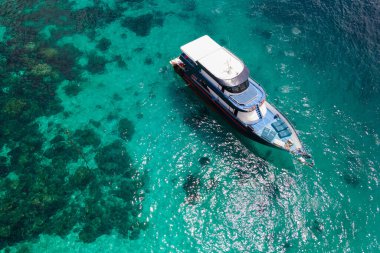 Tayland 'ın Phuket kentinde yaz tatili için popüler bir yer olan Racha Adası ya da Koh Racha' daki turkuaz berrak su üzerinde birlikte demirleyen eğlence aracı ya da dalış teknesinin hava görüntüsü..