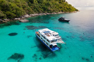 PHUKET, THAILAND - 24 Nisan 2025: Tatil teknesinin havadan görünüşü veya turkuaz berrak su üzerinde demirleyen tüplü dalış botu Racha Adası veya Koh Racha, yaz tatili için popüler bir durak