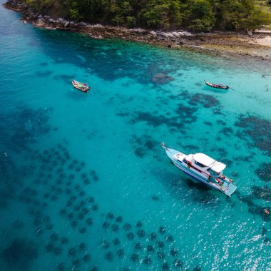 Koh Racha Yai Adası 'nın havadan görünüşü turnuva teknesi ve uzun kuyruklu teknesi körfezin önünde demirliyor. Yaz tatili aktiviteleri için popüler bir yer.