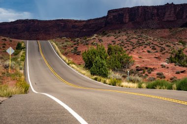 Birleşik Devletler 'in Utah kentinin her iki tarafındaki aşınmış kırmızı kumtaşı manzarasına sahip boş manzaralı köy yolu.