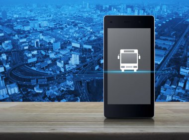 Otobüs düz ahşap masa şehir Kulesi, sokak ve expressway, iş ulaşım hizmeti kavramı üzerinde modern akıllı telefonun ekranında simgesine