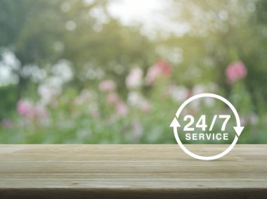 24 saat hizmet simgesine ahşap masa üzerinde bulanıklık pembe çiçek ve ağaç, tam zamanlı hizmet anlayışı