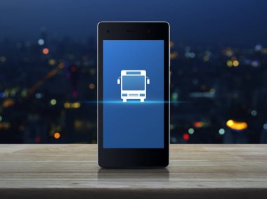 Otobüs düz ahşap masa üzerinde modern akıllı telefonun ekranında simgesine bulanıklık renkli gece ışık şehir Kulesi, iş ulaşım hizmeti kavramı