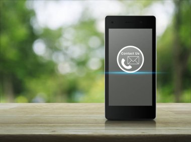 Ahşap masa üzerinde modern akıllı telefon ekranında telefon ve posta kutsal kişilerin resmi düğme üzerinde park yeşil ağaç blur, kavramı bize