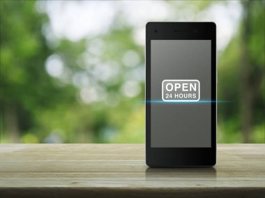 Ahşap masa üzerinde modern akıllı telefonun ekranında simgesine bulanıklık Park, iş tam zamanlı hizmet kavramı yeşil ağaç 24 saat açık