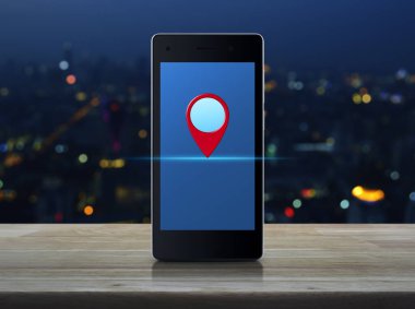 Ahşap masa üzerinde üzerinde modern akıllı telefon ekranında harita PIN konumu düğmesini bulanıklık renkli gece ışık şehir Kulesi, harita işaretçi gezinti kavramı