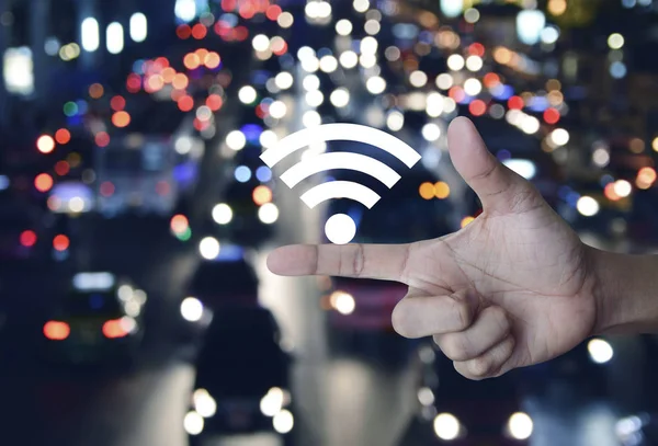 Wifi 图标在手指在模糊多彩的夜灯城市与汽车 技术和互联网概念 — 图库照片