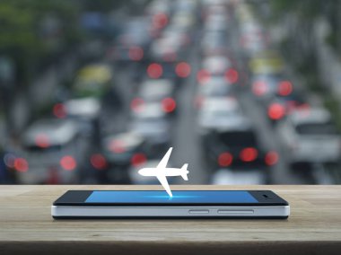 Ahşap masa üzerinde modern akıllı telefonun ekranında uçak simgesini bulanıklık rush saat araba ve yol, iş ulaşım kavramı ile