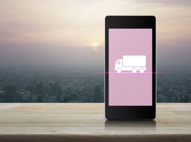 Kamyon düz ahşap masa üzerinde şehir Kulesi günbatımı, vintage tarzı, iş ulaşım hizmet kavramı, modern akıllı telefonun ekranında simgesine