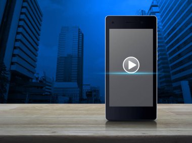 Ahşap masa ofis şehir Kulesi, iş müzik online kavramı üzerinde modern akıllı telefonun ekranında Oynat düğmesini