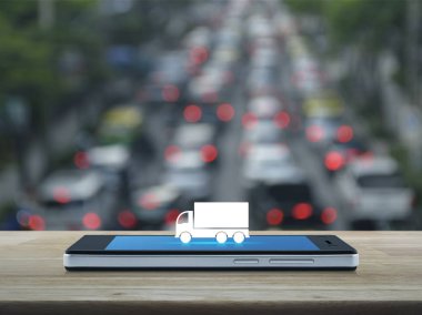Kamyon düz ahşap masa üzerinde modern akıllı telefonun ekranında simgesine bulanıklık rush saat araba ve yol, iş ulaşım hizmeti kavramı ile