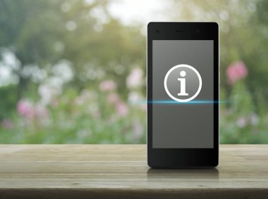 Ahşap masa üzerinde modern akıllı cep telefonu ekranda bilgi işareti simgesini bulanıklık pembe çiçek ve ağaç, iletişim online iş teknoloji kavramı