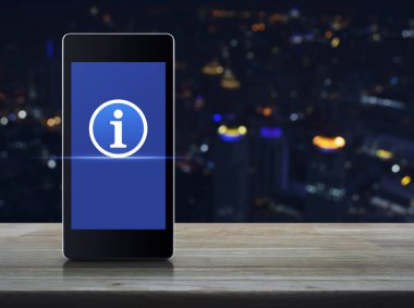 Bilgi işareti düz ahşap masa üzerinde modern akıllı cep telefonu ekran simgesine bulanıklık renkli gece ışık şehir kule ve gökdelen, işyeri internet müşteri hizmeti iletişim kavramı