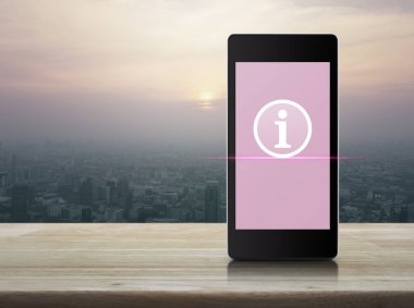 Ahşap masa üzerinde şehir kule ve gökdelen günbatımı, vintage tarzı, online iletişim iş kavramı, modern akıllı cep telefonu ekranda bilgi işareti simgesini